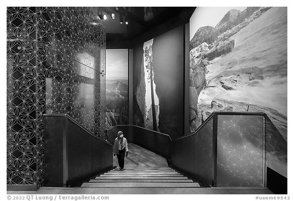 Visitor walking up stairs looking at mural prints, USA Pavilion. Expo 2020, Dubai, United Arab Emirates