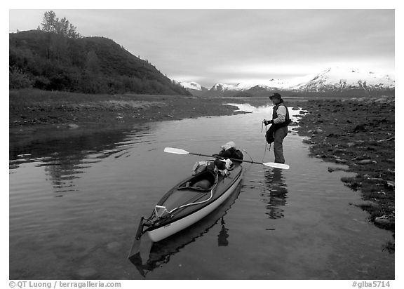 Kayaker tows kayak into a shallow tidal channel into Scidmore Bay. Glacier Bay National Park, Alaska