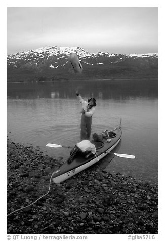 Kayaker unloading the kayak by throwing stuff sacks out. Glacier Bay National Park, Alaska