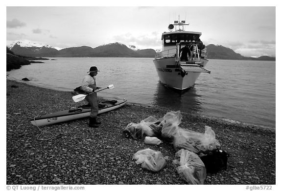 Kayaker standing with gear wrapped in plastic bags after drop-off. Glacier Bay National Park, Alaska