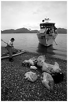 Kayaker standing with gear wrapped in plastic bags after drop-off. Glacier Bay National Park, Alaska (black and white)