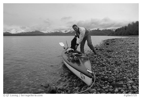 Kayaker loading gear into a double kayak. Glacier Bay National Park, Alaska