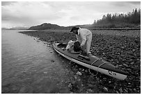 Kayaker unloading gear from a double kayak. Glacier Bay National Park, Alaska (black and white)