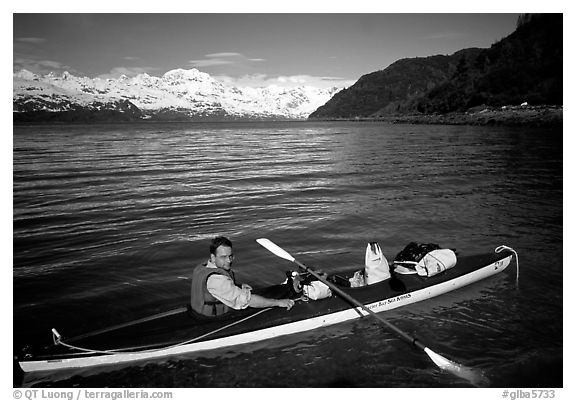 Kayaker sitting at a rear of a double kayak with the Fairweather range in the background. Glacier Bay National Park, Alaska