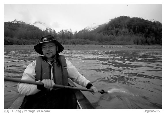 Kayaker paddling away from shore in Muir Inlet. Glacier Bay National Park, Alaska