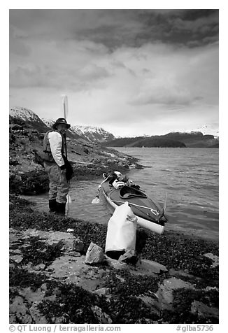 Kayaker standing next to dry bag and kayak on a small island in Muir Inlet. Glacier Bay National Park, Alaska