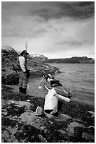 Kayaker standing next to dry bag and kayak on a small island in Muir Inlet. Glacier Bay National Park, Alaska (black and white)