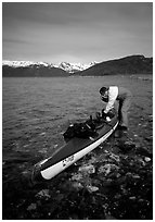 Kayaker tying up gear on top of the kayak,  East Arm. Glacier Bay National Park, Alaska (black and white)