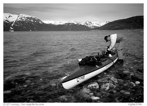 Kayaker tying up gear on top of the kayak,  East Arm. Glacier Bay National Park, Alaska