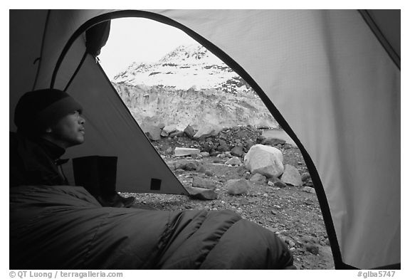 Camper lying in sleeping bag looks at Lamplugh Glacier. Glacier Bay National Park, Alaska