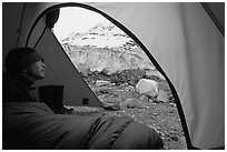Camper lying in sleeping bag looks at Lamplugh Glacier. Glacier Bay National Park, Alaska (black and white)