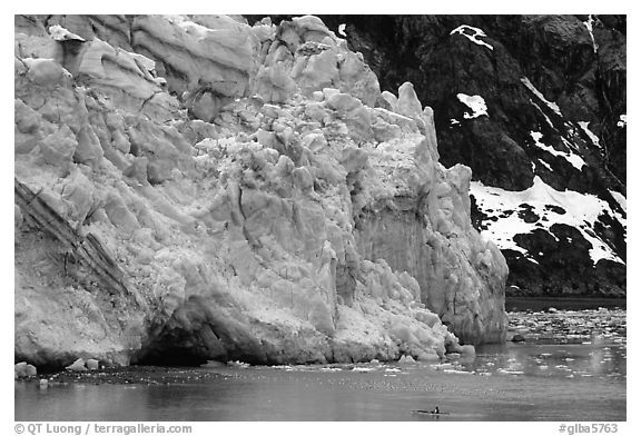 Kayaker paddling bellow Lamplugh Glacier. Glacier Bay National Park, Alaska