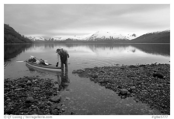 Kayaker standing in Scidmore Bay next to a shallow tidal channel. Glacier Bay National Park, Alaska