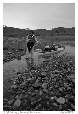 Kayaker towing the kayak in the narrowest part of a tidal channel into Scidmore Bay. Glacier Bay National Park, Alaska