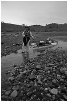 Kayaker towing the kayak in the narrowest part of a tidal channel into Scidmore Bay. Glacier Bay National Park, Alaska (black and white)