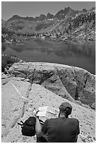 Hiker looking at map in front of lake, lower Dusy Basin. Kings Canyon National Park, California (black and white)