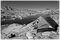 Man sitting in tent above lake, Dusy Basin. Kings Canyon National Park, California (black and white)