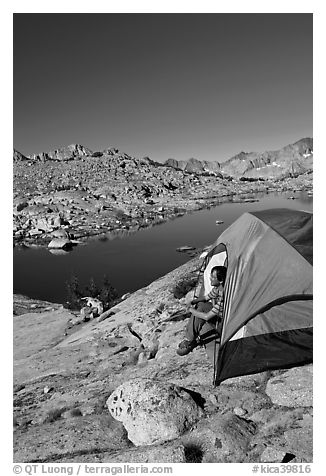 Man looking out from tent above lake, morning, Dusy Basin. Kings Canyon National Park, California