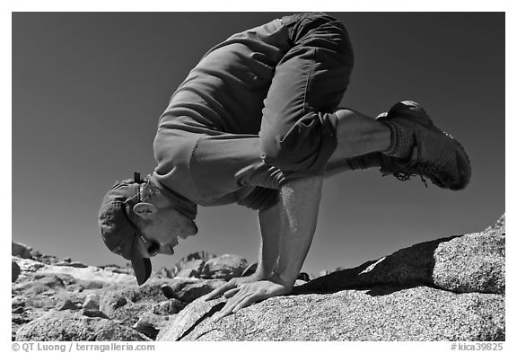 Hiker balancing on hands on rock, Bishop Pass. Kings Canyon National Park, California