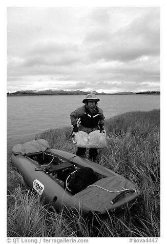 Canoeist unloading the canoe on a grassy riverbank. Kobuk Valley National Park, Alaska