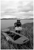 Canoeist unloading the canoe on a grassy riverbank. Kobuk Valley National Park, Alaska (black and white)