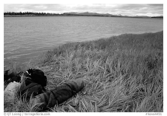 Gear and folded  canoe on a grassy riverbank of the Kobuk River. Kobuk Valley National Park, Alaska