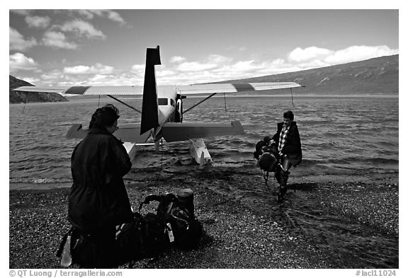 Pilot unloading a backpack from the floatplane on Lake Turquoise. Lake Clark National Park, Alaska