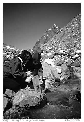 Hikers filing up a water container with a filter. Lake Clark National Park, Alaska