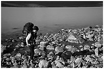 Backpacker walking on rocks on the shore of Turquoise Lake. Lake Clark National Park, Alaska (black and white)