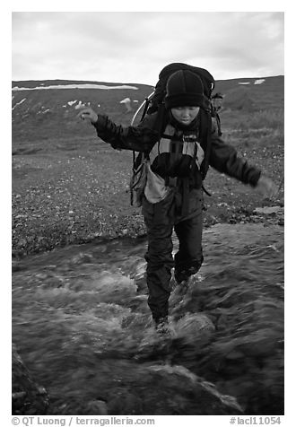 Backpacker balancing herself while crossing a stream. Lake Clark National Park, Alaska