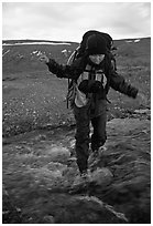 Backpacker balancing herself while crossing a stream. Lake Clark National Park, Alaska (black and white)