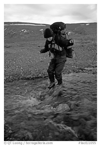 Backpacker crossing a stream on pebbles. Lake Clark National Park, Alaska