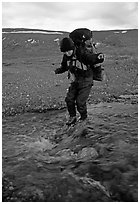 Backpacker crossing a stream on pebbles. Lake Clark National Park, Alaska (black and white)