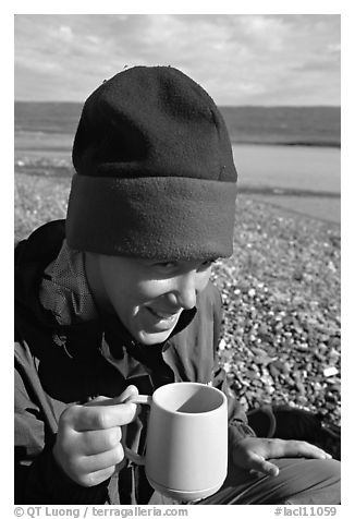 Backpacker drinking from a cup, with mosquitoes on her hat. Lake Clark National Park, Alaska
