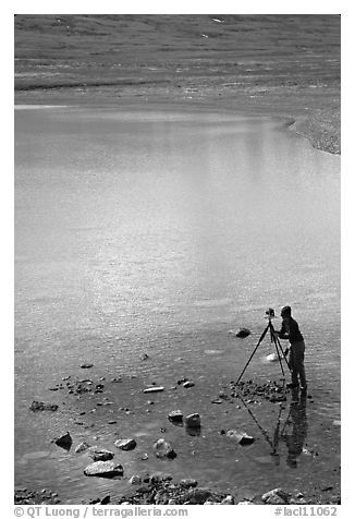 Large format photographer with tripod on the shores of Turquoise Lake. Lake Clark National Park, Alaska