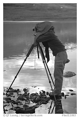 Large format photographer under dark cloth on the shores of Turquoise Lake. Lake Clark National Park, Alaska