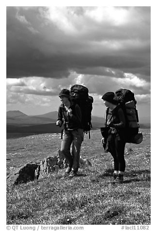 Two women backpackers pausing in the tundra with alpine flowers in the background. Lake Clark National Park, Alaska