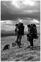 Two women backpackers pausing in the tundra with alpine flowers in the background. Lake Clark National Park, Alaska (black and white)