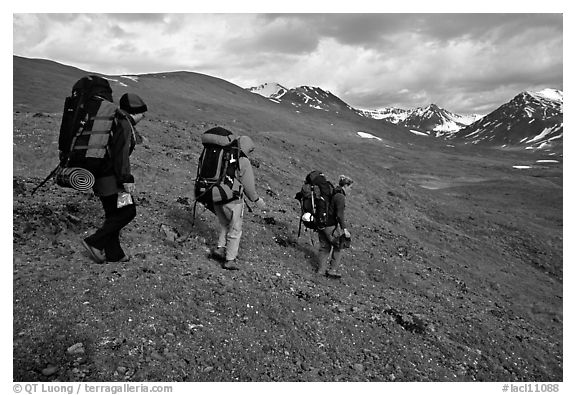Backpackers with big packs going down a slope. Lake Clark National Park, Alaska