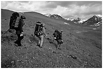 Backpackers with big packs going down a slope. Lake Clark National Park, Alaska (black and white)