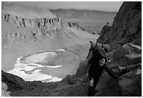 Woman with backpack pausing on steep terrain above Iceberg Lake. Sequoia National Park, California (black and white)