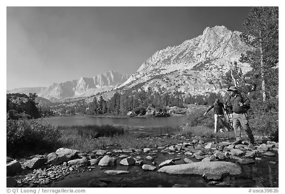 Hikers crossing stream on rocks at Long Lake, John Muir Wilderness. Kings Canyon National Park, California