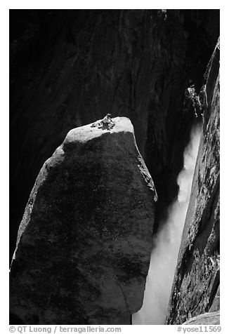 Climber resting on top of Lost Arrow spire with Yosemite Falls behind. Yosemite National Park, California