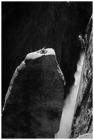 Climber resting on top of Lost Arrow spire with Yosemite Falls behind. Yosemite National Park, California (black and white)