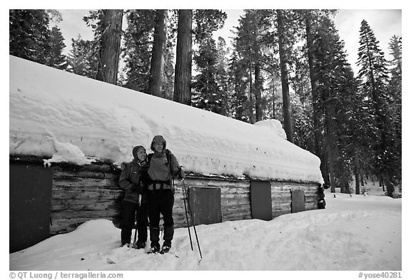 Skiing couple in front of the Mariposa Grove Museum in winter. Yosemite National Park, California