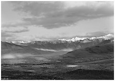 Tarn lakes, tundra, and snowy mountains of Alaska Range with patches of light. Denali National Park, Alaska, USA. (black and white)