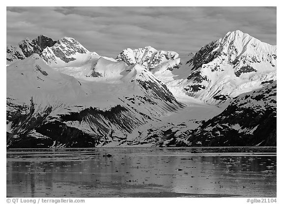 Coastal mountains with glacier dropping into icy fjord. Glacier Bay National Park, Alaska, USA.