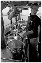 Chef cooking aboard small boat. Glacier Bay National Park, Alaska, USA. (black and white)