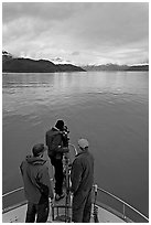 Film crew working on the bow of a small boat. Glacier Bay National Park, Alaska, USA. (black and white)