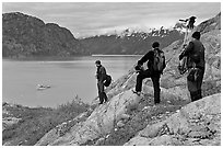 Film crew carrying a motion picture camera down rocky slopes. Glacier Bay National Park, Alaska, USA. (black and white)